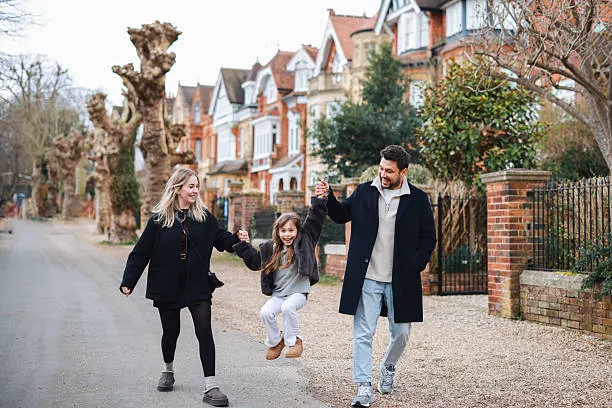 A family walking along a tree-lined street of red-brick homes
